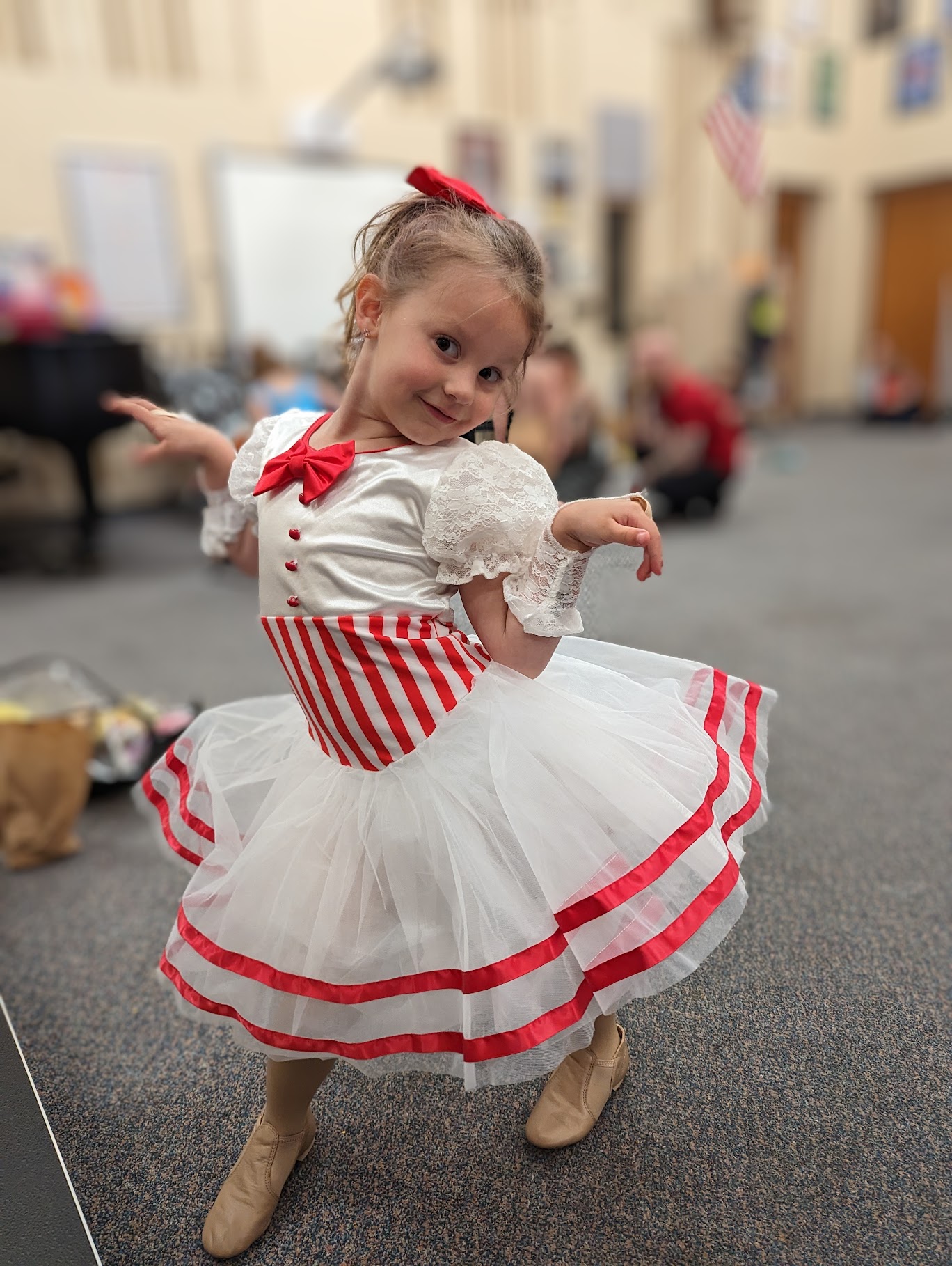 Five year old girl in a cute pose standing in a red and white dress.