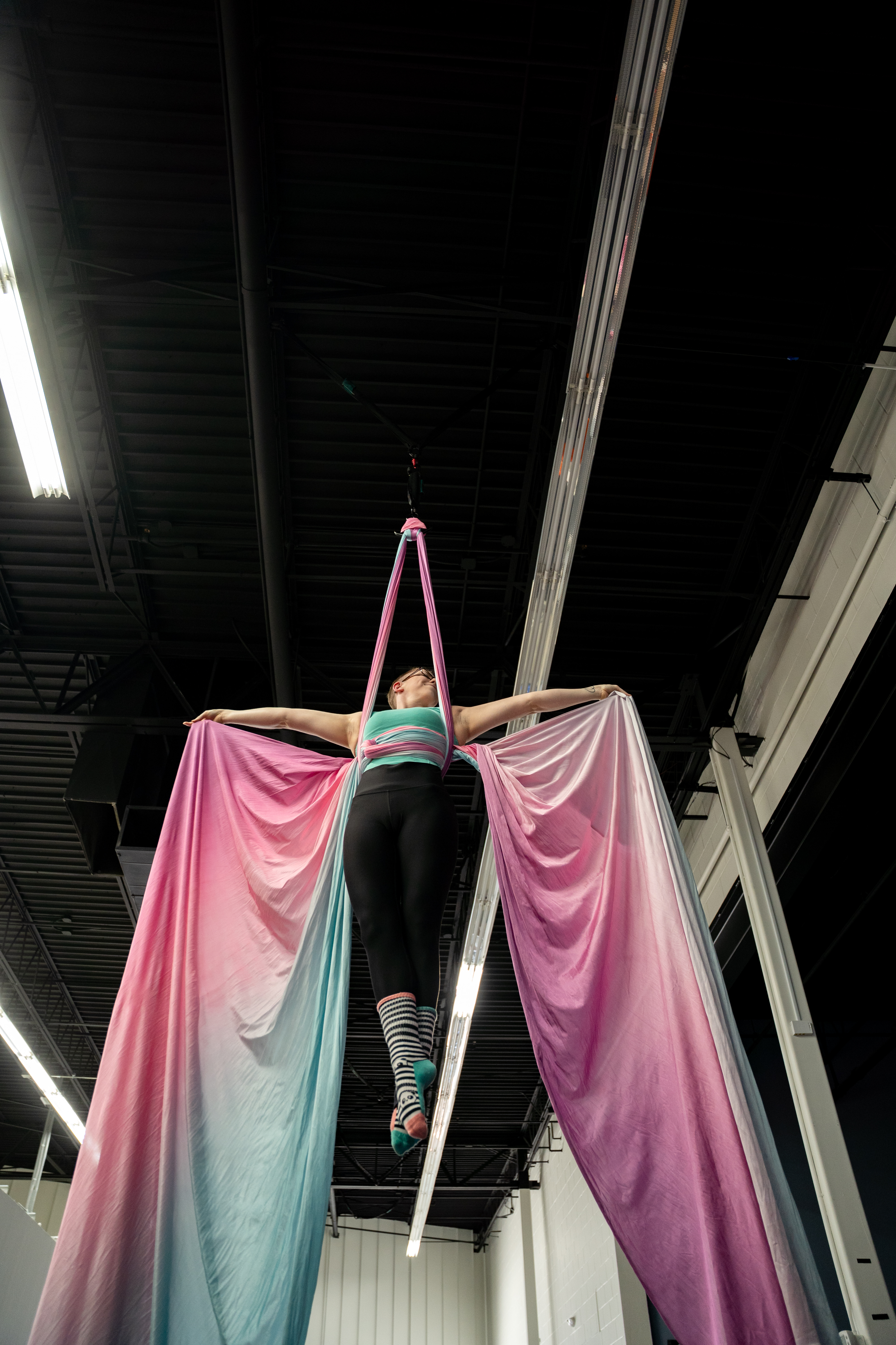 Physio Flows instructor performing Butterfly Wings on silks inside the Physio Flows aerial studio.
